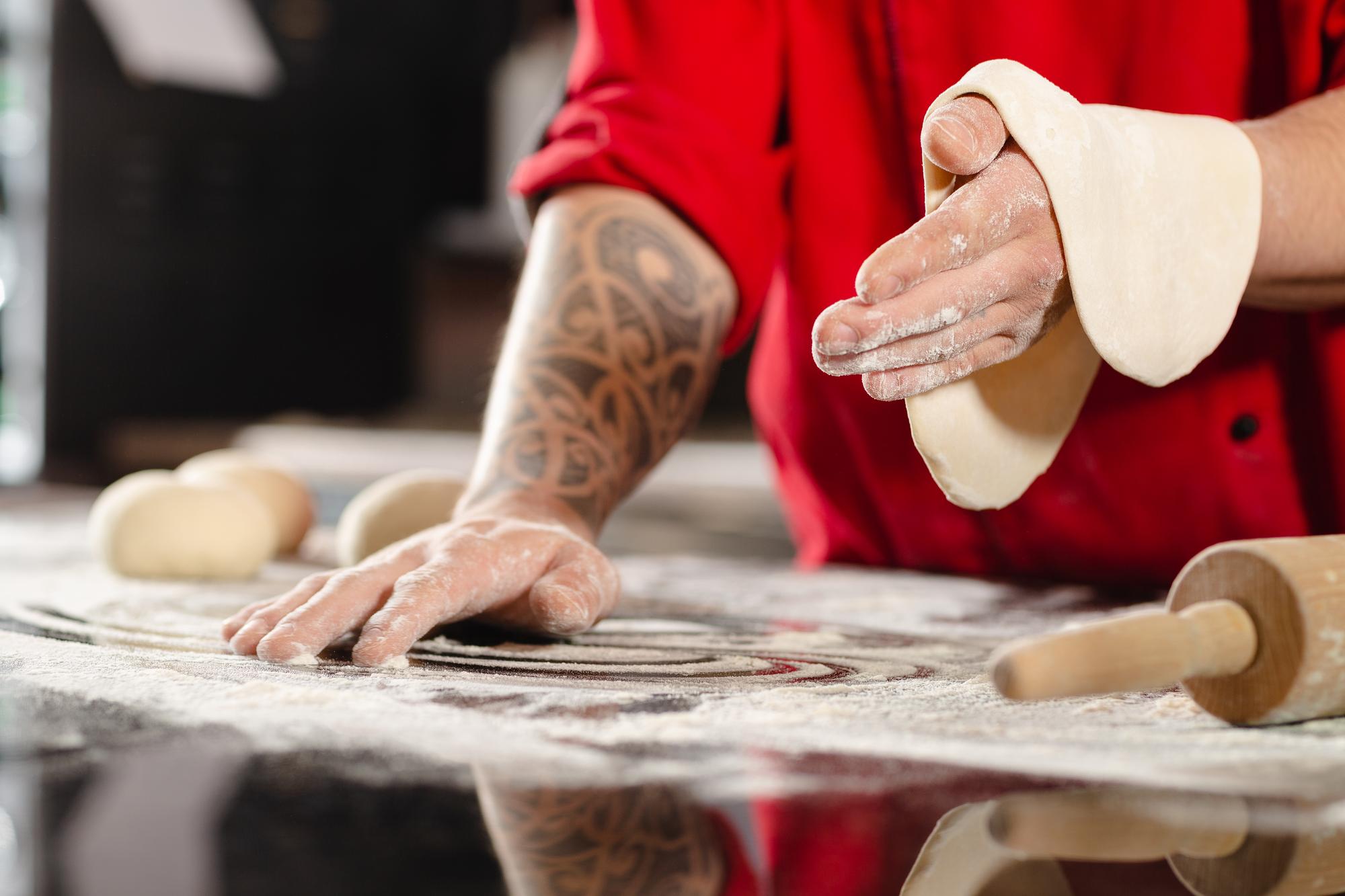 Hands kneading dough on marble surface